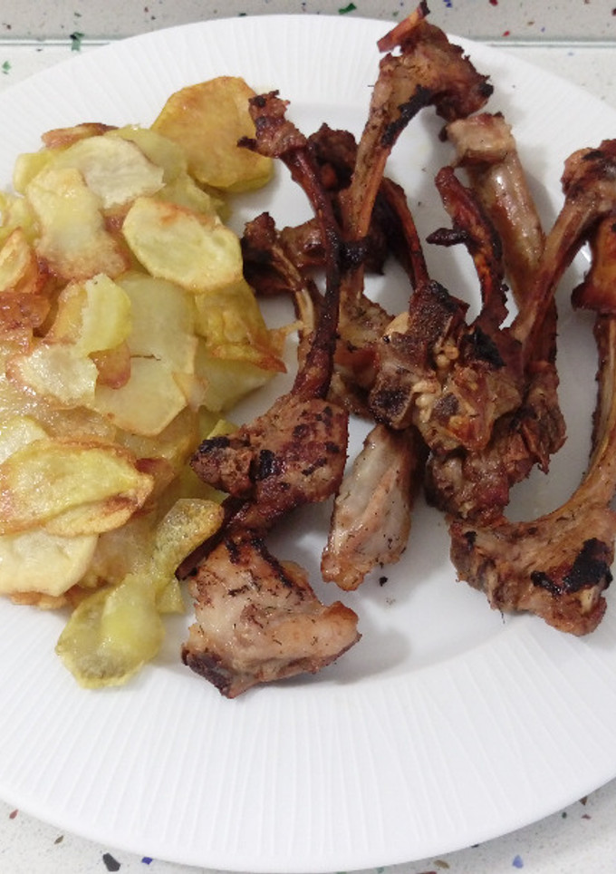 Una foto de Barbacoa de chuletillas de cordero con patatas fritas