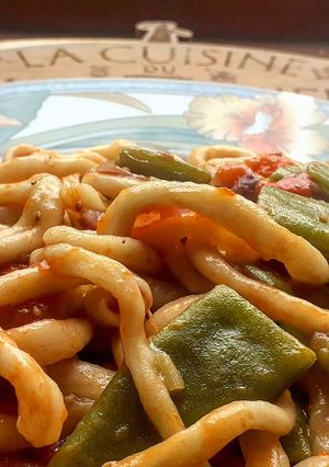 Une photo de I pici avec tomates et haricots verts