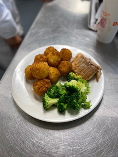 A picture of Spanish rice balls with sliced Turkey and sauté broccoli.