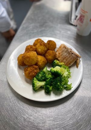 A picture of Spanish rice balls with sliced Turkey and sauté broccoli.