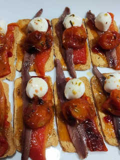 Una foto de Mini tostas con tomate cherrys confitados, mermelada de pimiento y anchoas