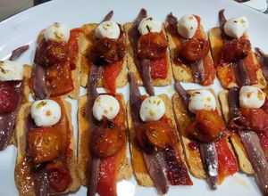 Foto principal de Mini tostas con tomate cherrys confitados, mermelada de pimiento y anchoas