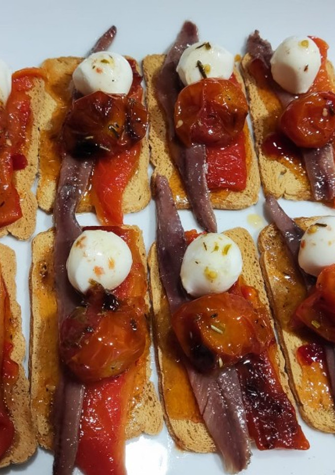 Una foto de Mini tostas con tomate cherrys confitados, mermelada de pimiento y anchoas