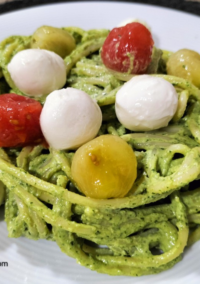 Una foto de Spaghetti al pesto de rúcula y nueces con cherrys y mozzarella