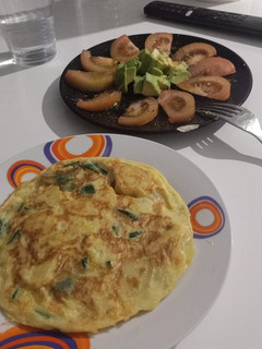 Una foto de Tortilla de patatas con calabacín y tomate aliñado con aguacate