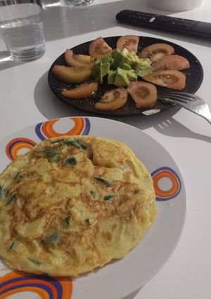 Una foto de Tortilla de patatas con calabacín y tomate aliñado con aguacate