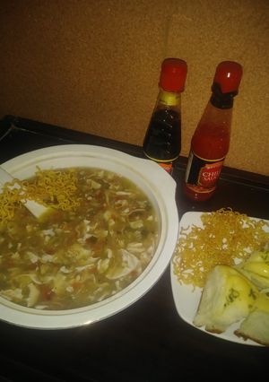 A picture of Chicken manchow soup with scallion garlic bread.