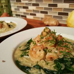 A picture of Butter poached shrimp with parmasan spinach orzo risotto.