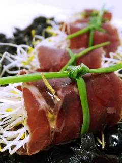 Una foto de Rollitos de cecina con germinados y sirope de membrillo sobre tierra de aceitunas negras y aceite aromatizado de romero