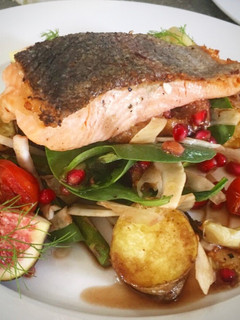 A picture of Seared salmon on figs, roasted potatoes, fennel spinach and pomegranate dressing.