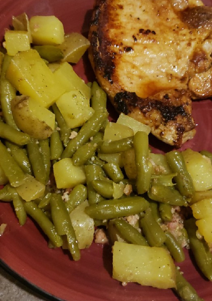A picture of 1 pan potatoes and greenbeans with pan fried bone-in pork chops.