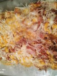 Una foto de Patatas fritas con bacon, jamón y queso rallado