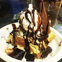 A picture of Waffles topped with Vanilla Ice cream.