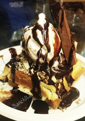 A picture of Waffles topped with Vanilla Ice cream.