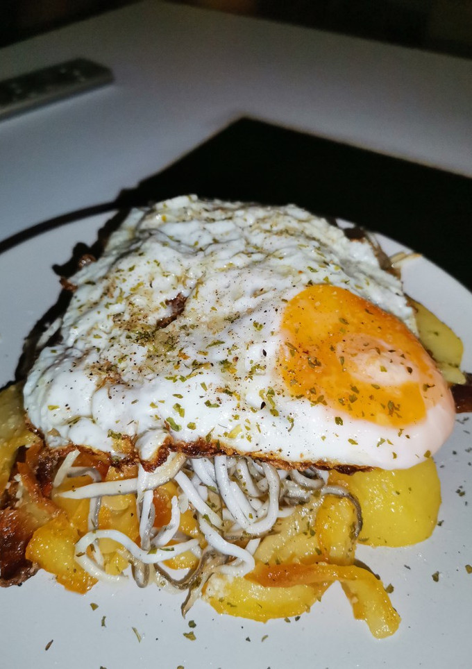 Una foto de Patatas al ajo cabañil con gulas y huevo frito