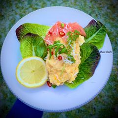 A picture of Scrambled eggs, smoke salmon with lefy greens on bed of sourdough bread.
