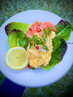 A picture of Scrambled eggs, smoke salmon with lefy greens on bed of sourdough bread.