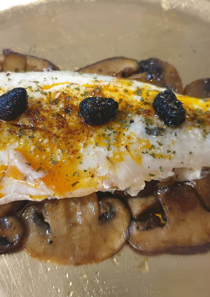 Una foto de Lubina asada sobre cama de setas de soja y pimentón🌶ajos negros