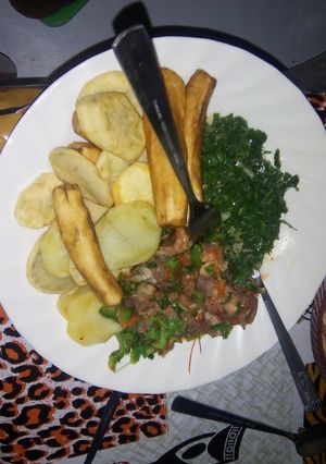 A picture of Deep fried potatoes and green bananas served with beef stew and spinach.