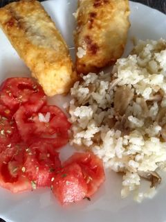 Una foto de Merluza frita con guarnición de arroz con setas y tomate