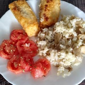 Merluza frita con guarnición de arroz con setas y tomate