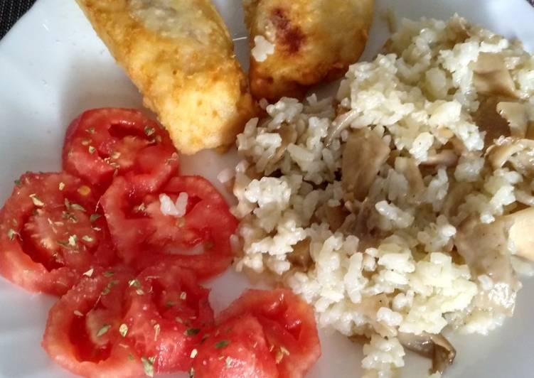 Merluza frita con guarnición de arroz con setas y tomate