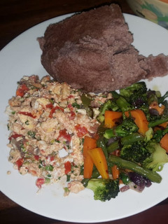 A picture of Brown ugali, fried eggs and mixed vegetables.