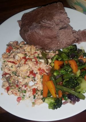 A picture of Brown ugali, fried eggs and mixed vegetables.