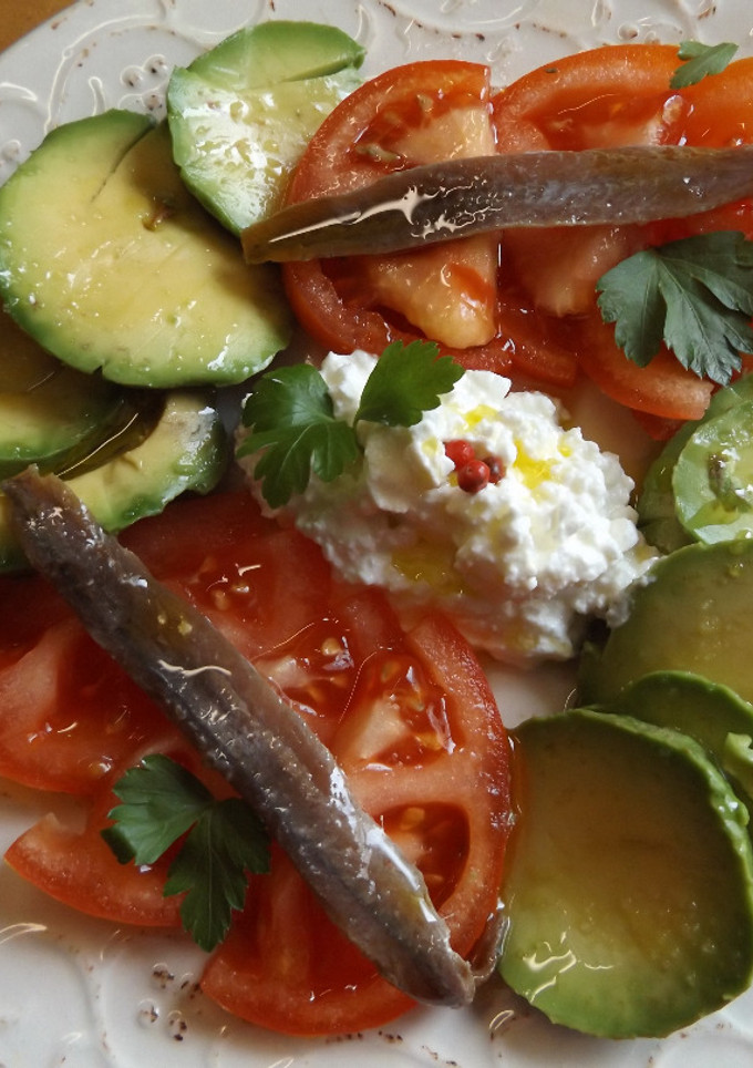 Una foto de Ensalada de aguacate y tomate con anchoas y queso granulado