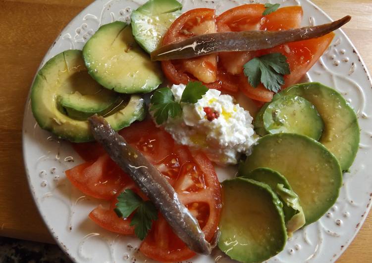 Ensalada de aguacate y tomate con anchoas y queso granulado