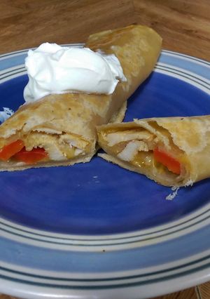 A picture of Seasoned Chicken & cheese wrap with bell peppers and sour cream..