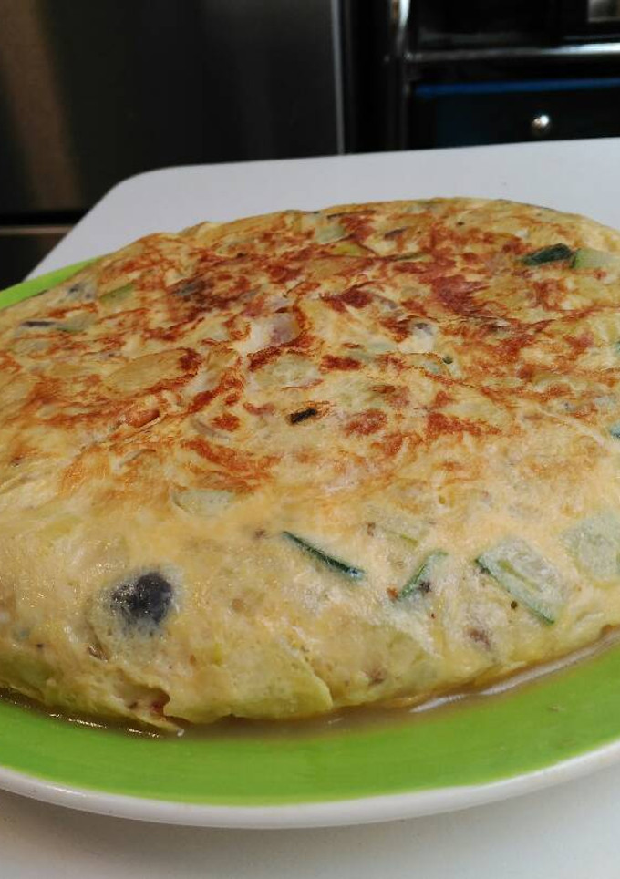 Una foto de Tortilla de patata, calabacín, setas y queso