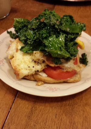 A picture of kale,tomato and cream cheese breakfast sandwich.
