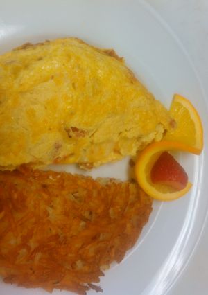 A picture of Good breakfast ham and tomato omelette with hash brown.