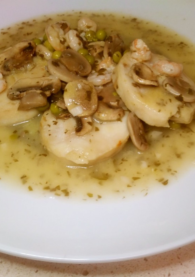 Una foto de Merluza en salsa verde con guarnición de gambas y champiñones