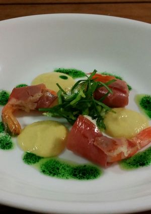 A picture of PROSCIUTTO wrapped PRAWNS, CORN PUREE + PESTO OIL.