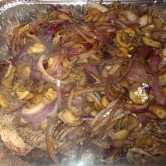 A picture of Ribeye steak smothered in onions and mushrooms.
