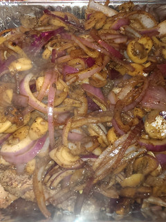 A picture of Ribeye steak smothered in onions and mushrooms.
