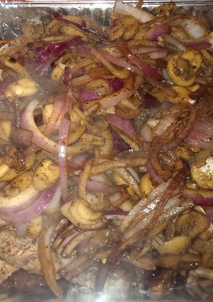 A picture of Ribeye steak smothered in onions and mushrooms.