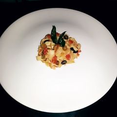 A picture of tomato concassé pasta with crispy basil.
