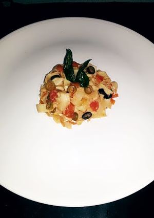 A picture of tomato concassé pasta with crispy basil.