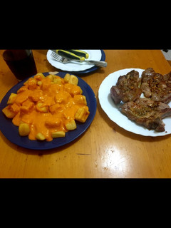 Una foto de Patatas con salsa brava caliente y chuletas de cabezá