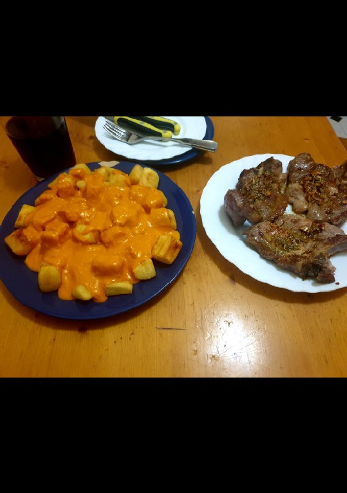 Una foto de Patatas con salsa brava caliente y chuletas de cabezá