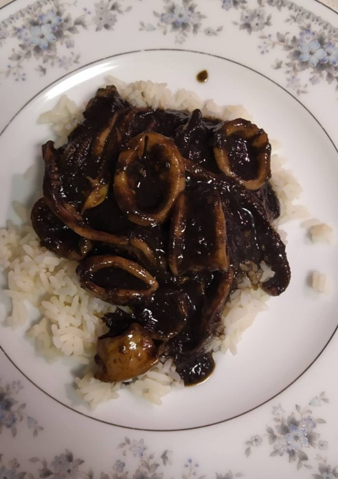 Una foto de Calamares encebollados en tinta con arroz blanco