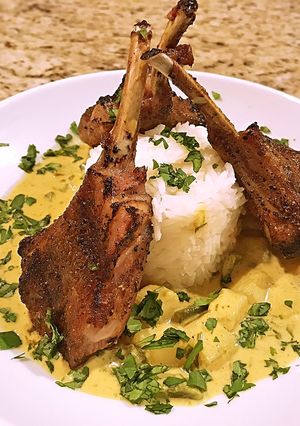 A picture of Potato in yellow curry sauce with grilled lamp chops.