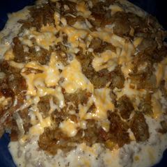 A picture of Cheesy hash brown skillet with sunny side up eggs and sausage gravy.