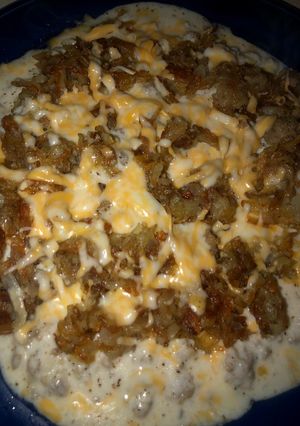 A picture of Cheesy hash brown skillet with sunny side up eggs and sausage gravy.