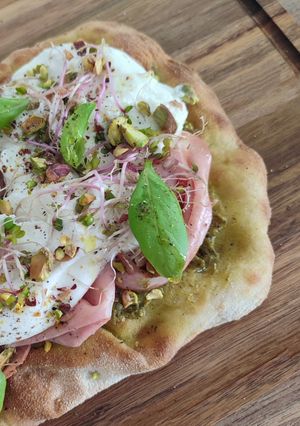 Une photo de Pinsa pesto mortadelle pistache