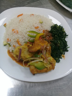 A picture of Oven baked chicken, steamed vegetable rice n fried sukuma wiki.