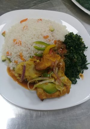 A picture of Oven baked chicken, steamed vegetable rice n fried sukuma wiki.